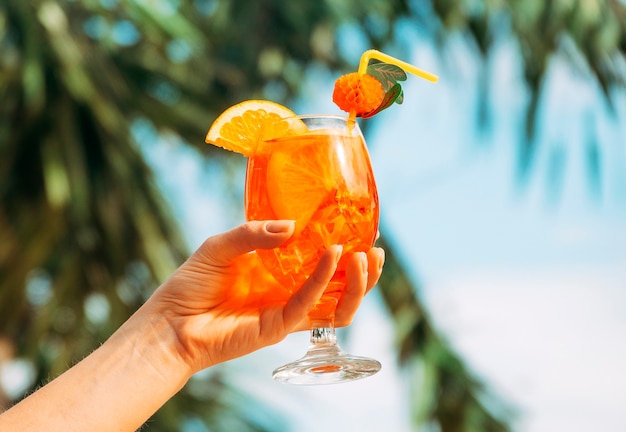 Foto gratuita bicchiere di arancia fresca brillante in mano