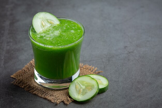 Glass of fresh cucumber juice on dark background