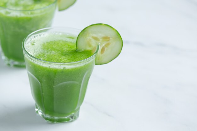 Glass of fresh cucumber juice on marble background