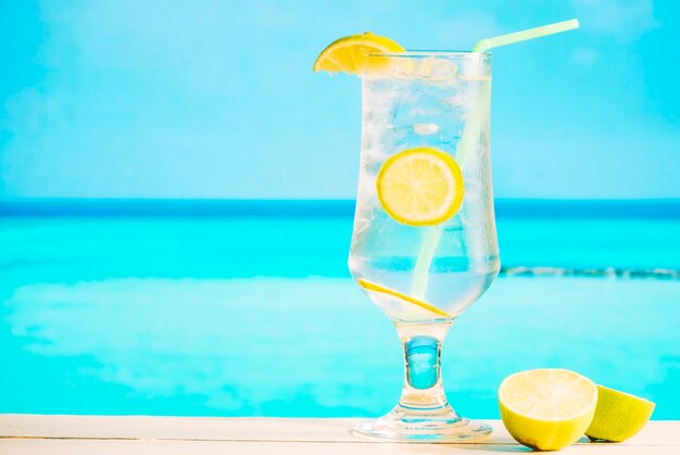 Glass of fresh lemon drink with straw and sliced lime