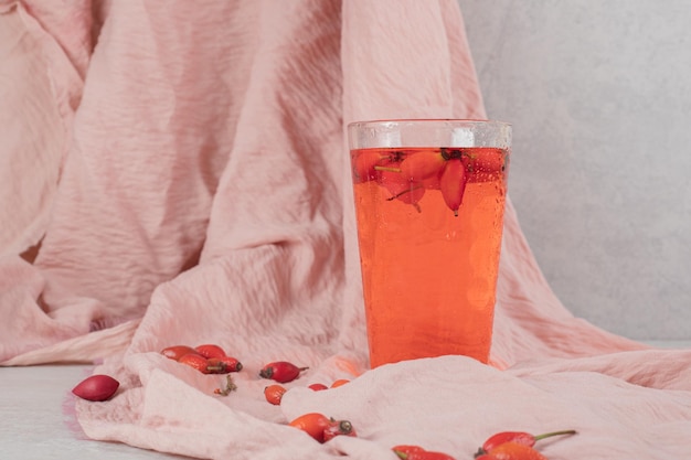 Glass of fresh lemonade with rosehips on cloth