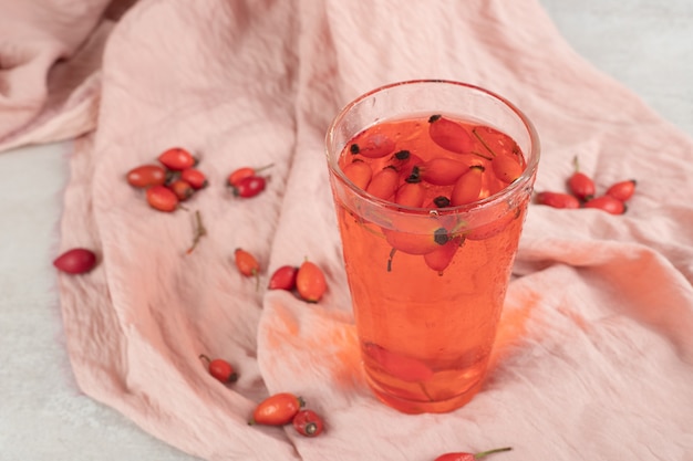 Glass of fresh lemonade with rosehips on cloth