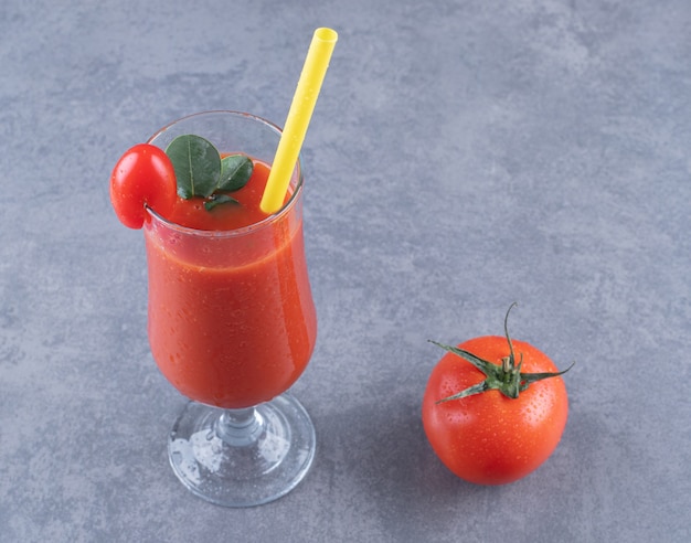 新鮮なトマトジュースと灰色の背景にトマトのガラス。