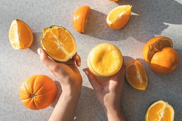 A glass of freshly squeezed orange juice and half an orange in female hands