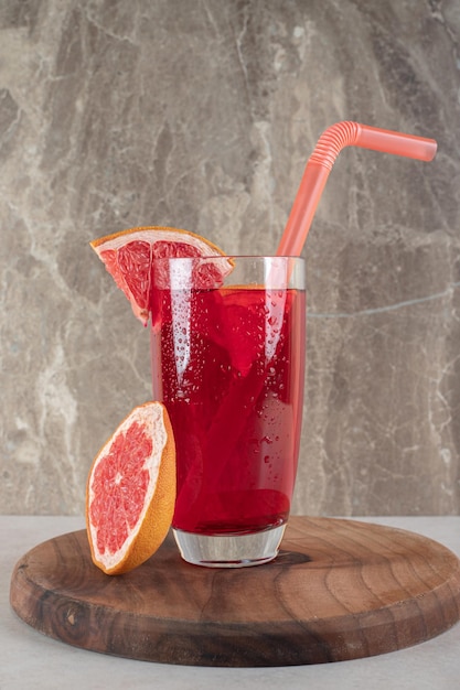 Glass of fruit juice with straw and grapefruit slices. 