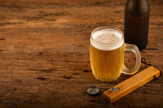 木製​の​テーブル​の​上に​冷たい​ビール​で​いっぱい​の​ガラス
