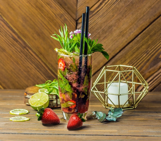 A glass of full tropical fruit cocktail with two pipes