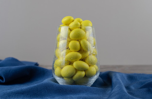 Free photo glass full of yellow gum on the towel, on the marble surface