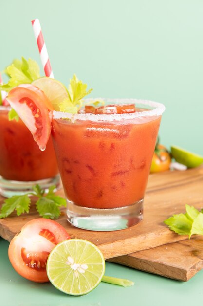 トマト ジュースのガラス グラス、緑の背景に分離されたトマトの新鮮な明るい束とライム、緑のパセリ。野菜ドリンク。