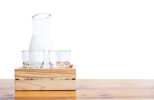흰색 배경에 격리된 탁자 위의 나무 상자에 유리잔과 우유가 든 병