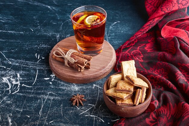 A glass of glintwine with lemon and cinnamon served with crackers. 