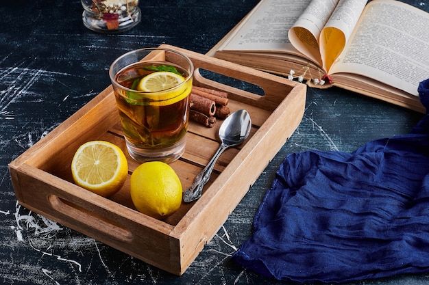 Free photo a glass of glintwine with lemons in a wooden tray.