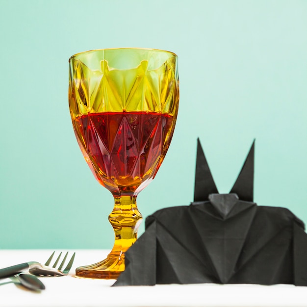 Glass goblet and bat origami standing on table