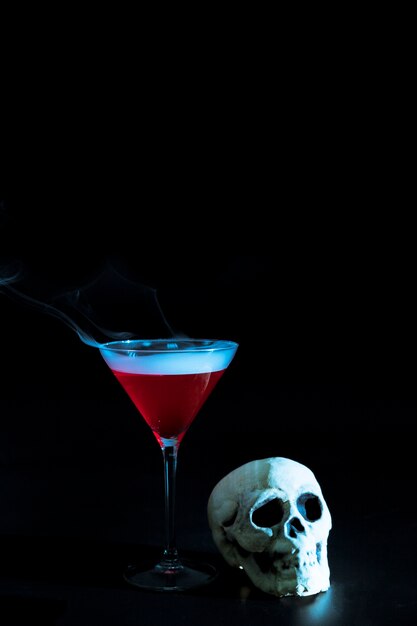 Стеклянный бокал с красной жидкостью и черепом