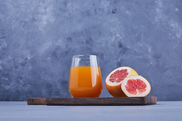 A glass of grapefruit juice with fruit slice around.