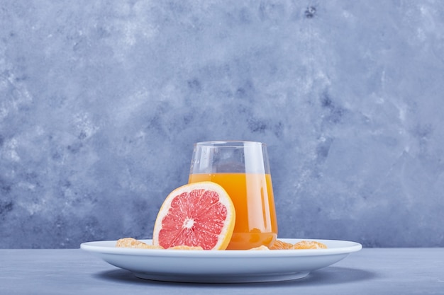A glass of grapefruit juice with fruit slice around.