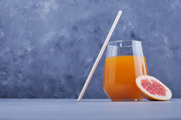 A glass of grapefruit juice with pipe.