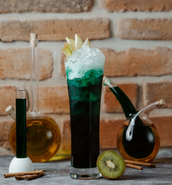 사과 조각과 얼음 조각으로 칵테일 녹색 알코올의 유리.