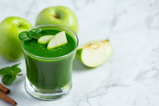 Glass of green apple healthy smoothie put next to fresh green apples