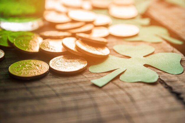 Free photo glass of green drink near heap of coins and paper shamrocks on table