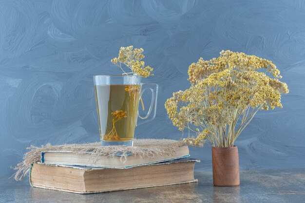 Glass of green tea and flowers on top of book.