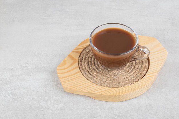 Glass of hot coffee on wooden plate