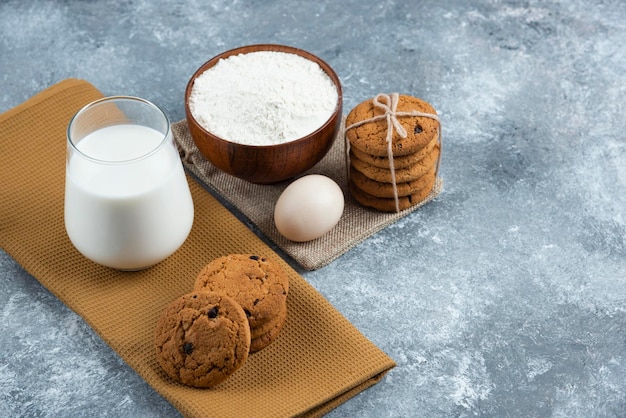 A glass of hot milk with delicious cookies on a gray table.