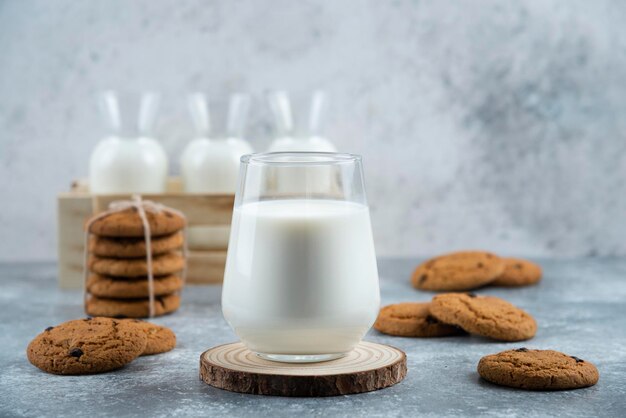 A glass of hot milk with delicious cookies on a gray table.