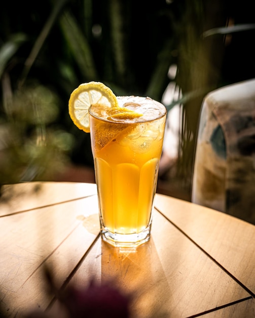 A glass of iced cockteil with lemon on wooden table