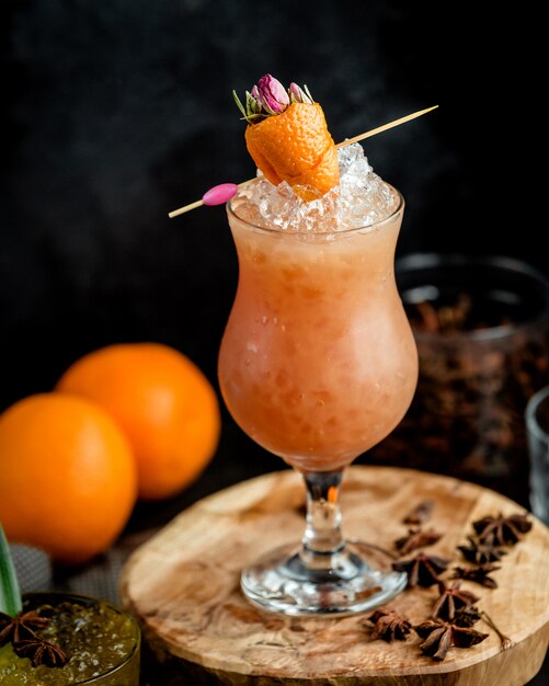 glass of iced orange cocktail garnished with orange zest in strawberry shape