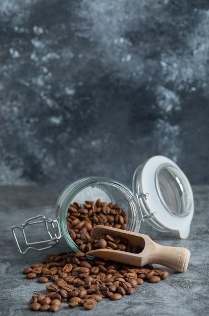 Стеклянная банка ароматных кофейных зерен на мраморном фоне