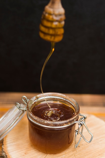 Glass jar full of honey with honey spoon