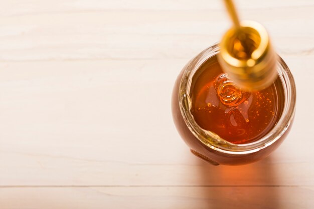 Glass jar full of honey with honey spoon