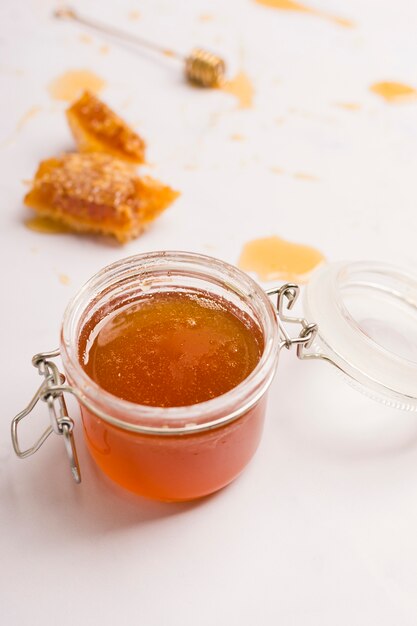 Glass jar full of honey with honey spoon