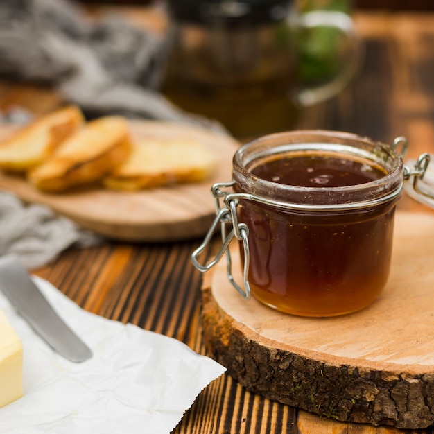 Glass jar full of honey with honey spoon