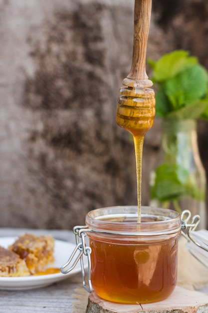 Glass jar full of honey with honey spoon