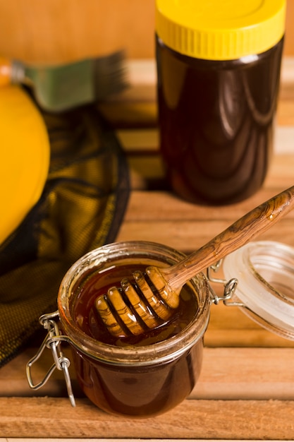 Glass jar full of honey with honey spoon