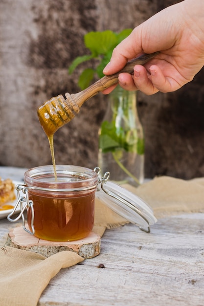 Glass jar full of honey with honey spoon