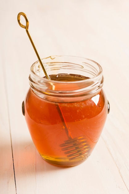 Glass jar full of honey with honey spoon