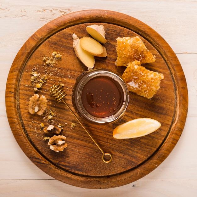 Glass jar full of honey on wooden tray