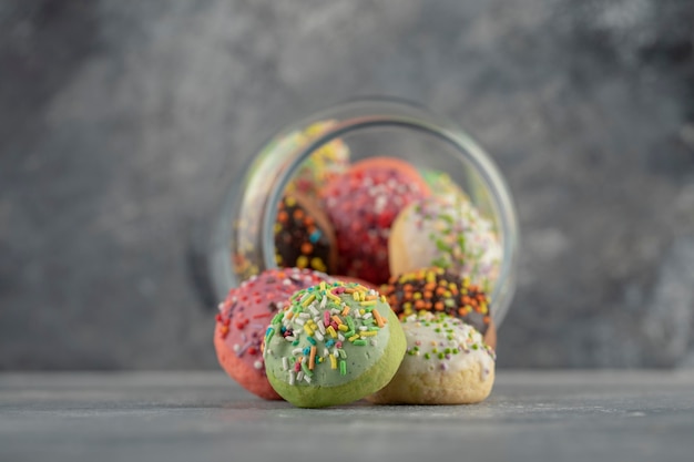 A glass jar full of small colorful doughnuts .