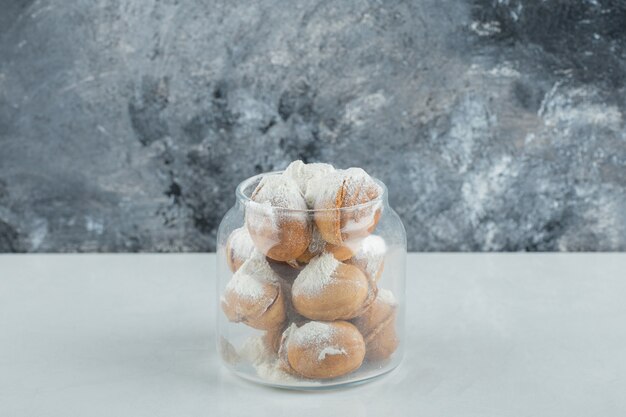 A glass jar full of sweet walnut shaped cookies.