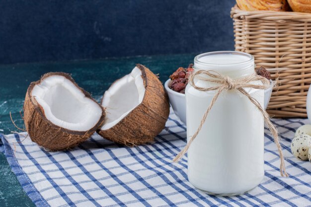 우유의 유리 항아리와 대리석 테이블에 절반 잘라 코코넛.