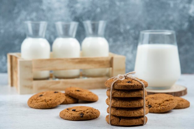 Glass and jar of milk with stack of cookies on marble table.