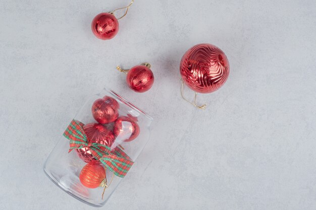 A glass jar of red Christmas balls on dark background. 