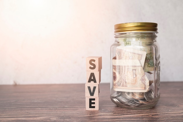 Glass jar for savings with wooden word