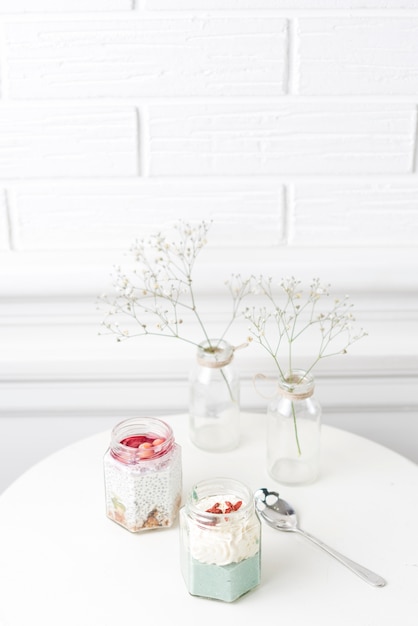 ガラスの瓶のスムージーと赤ちゃんが白いテーブルの上に花瓶に花を吸い込む