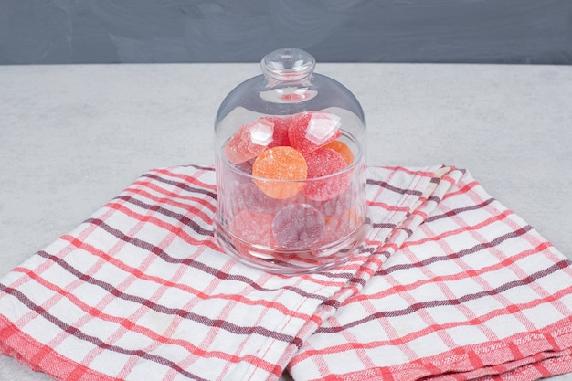 A glass jar of sweet candy on red tablecloth. High quality photo