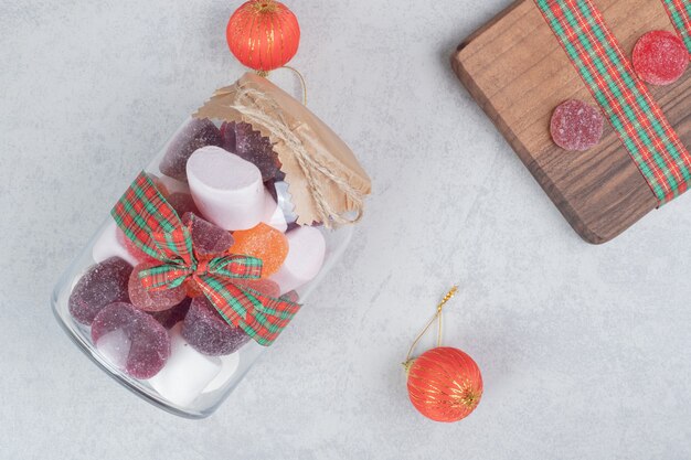 A glass jar of sweet candy on wooden board.