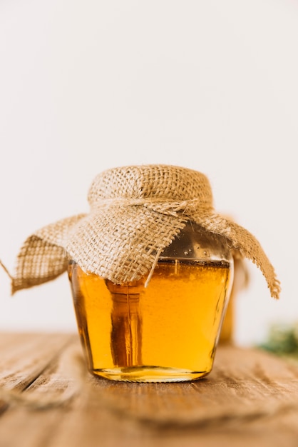 Glass jar of sweet honey on wooden table